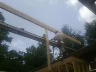 Carpenter setting a ridge beam over a new addition frame — Ice Dam Removal by Roofing Brothers in Golden