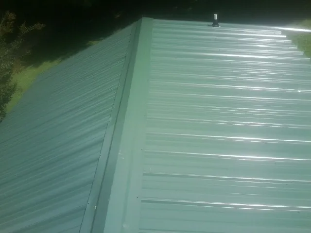 New green metal panels meeting at the ridge of a roof — Flat Roof Repair work by our crew in Golden