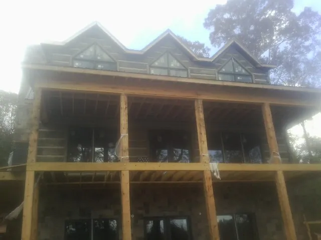 Dormers and porch framing on a large log home under construction — Roof Coating work by our crew in Golden