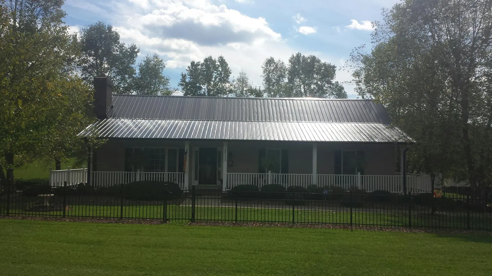 Gray metal roof on a brick ranch with a full width front porch — Gutter Guard Installation work by our crew in Golden
