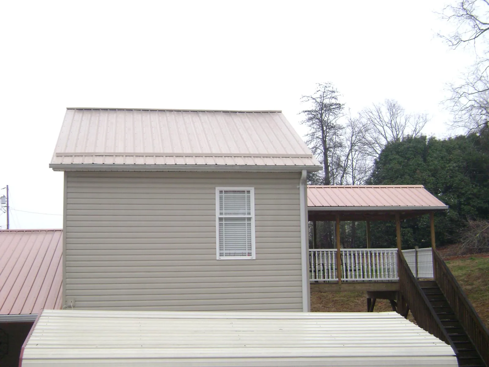 Tan metal roofs on a two story addition and attached porch, from a Roof Replacement job in Golden
